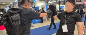 テロ対策特殊装備展（SEECAT）にて、来場者がFiveFieldsのグローブやミットを使用し、マットの上で受け身や使用感を体感している様子
